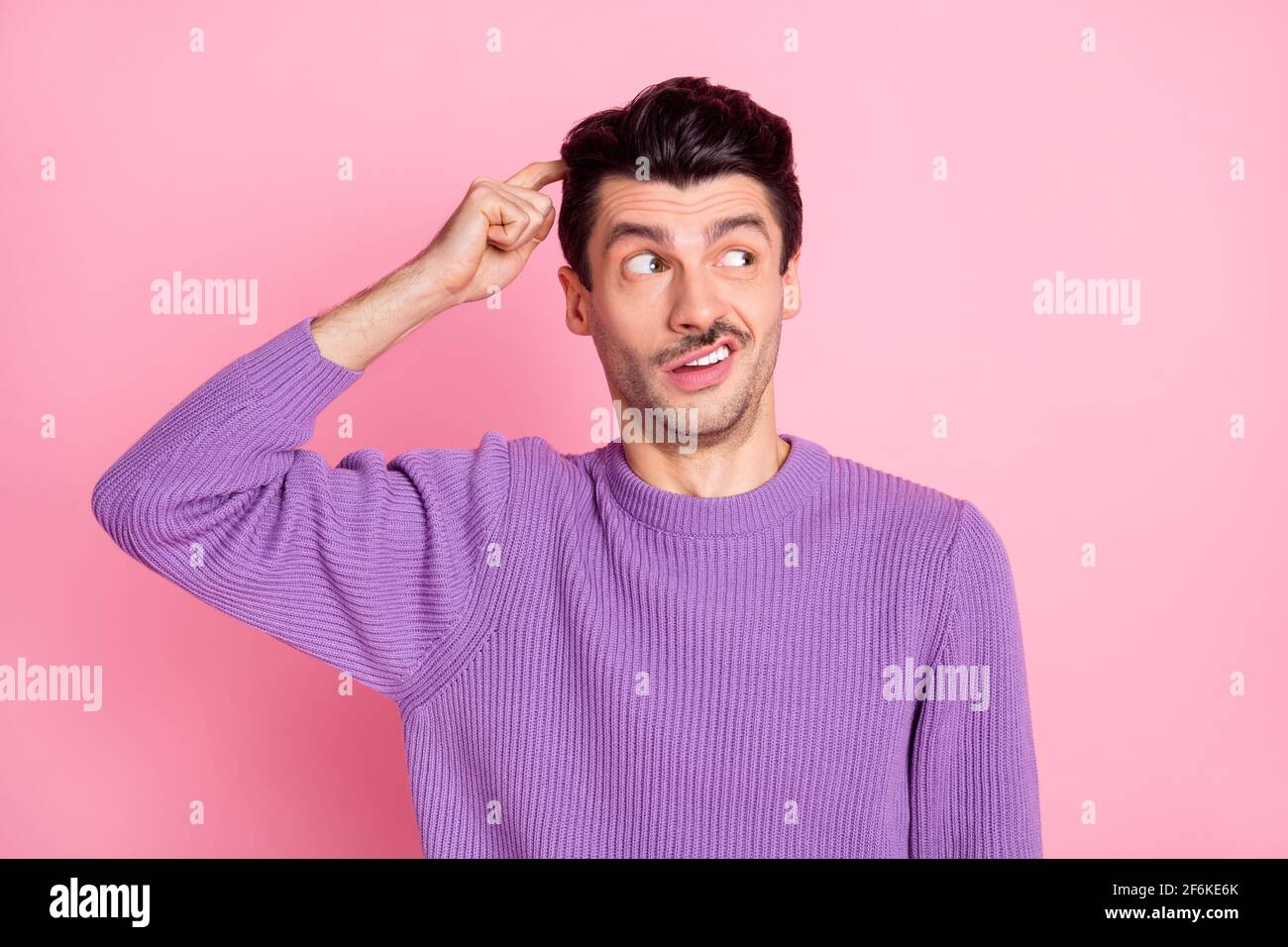 Foto di affascinante giovane uomo incerto vestito pullover viola dimenticare qualcosa testa dito isolato sfondo di colore rosa Foto Stock