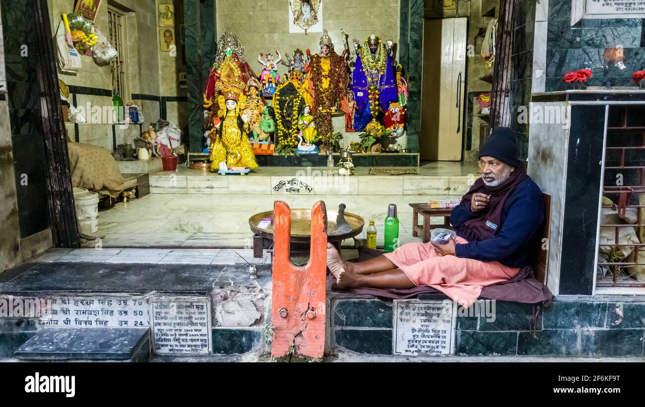 Kolkata, Bengala Occidentale, India - Gennaio 2018: Un uomo indiano seduto al di fuori di un colorato tempio indù in un vecchio quartiere nella città di Kolkata. Foto Stock