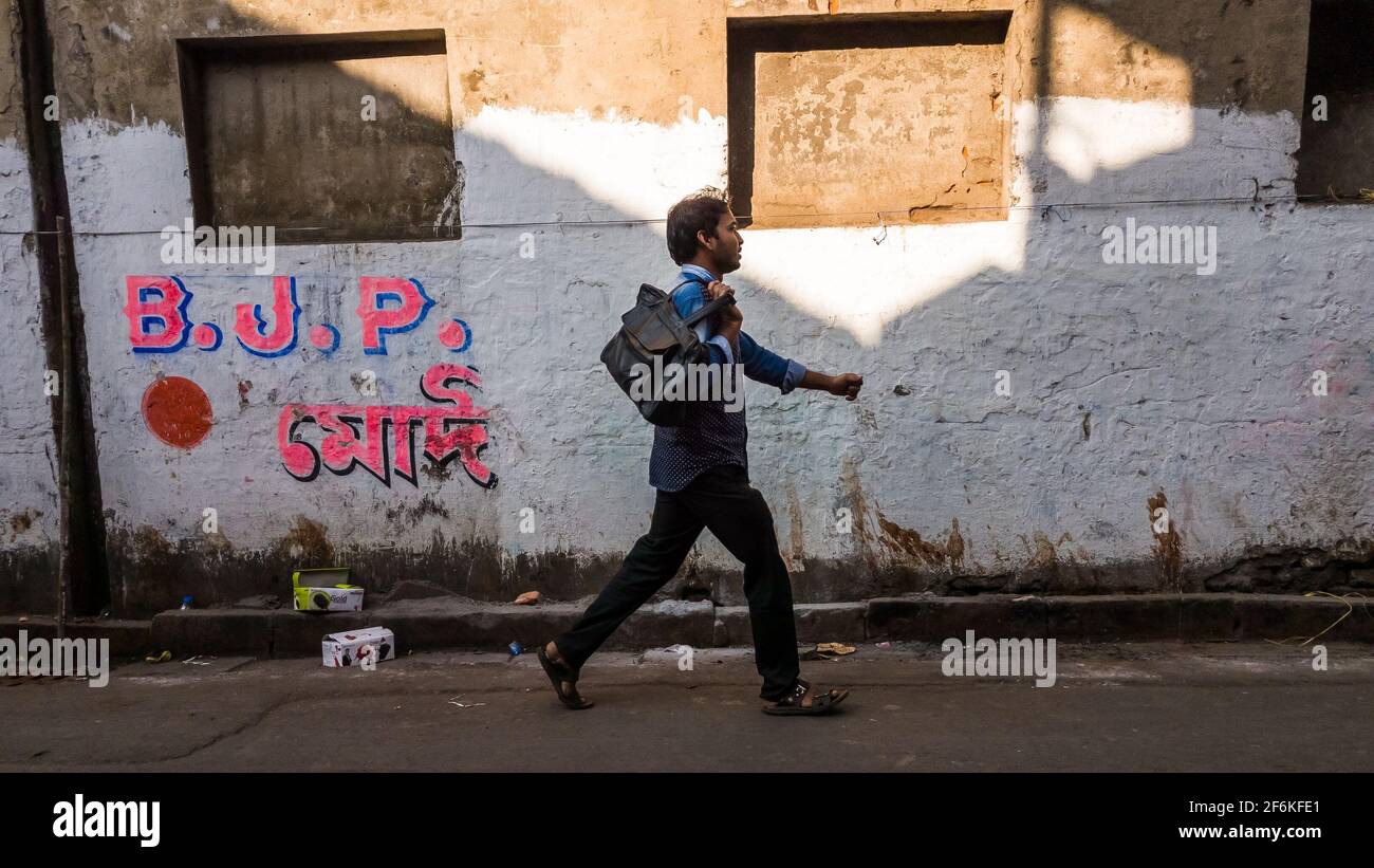 Kolkata, Bengala Occidentale, India - Gennaio 2018: Un uomo indiano che passa accanto a un muro grugnoso dipinto con la campagna politica del Bharatiya Janata Party aka Foto Stock