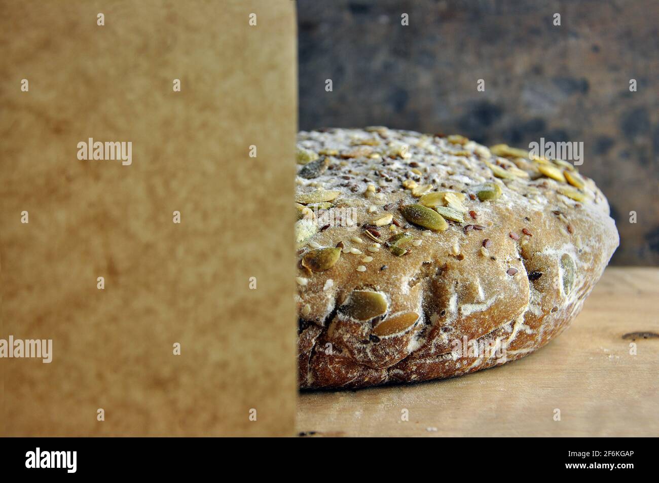 Pane con semi su una tavola di legno. Carta in primo piano. Spazio vuoto per il testo. Foto Stock
