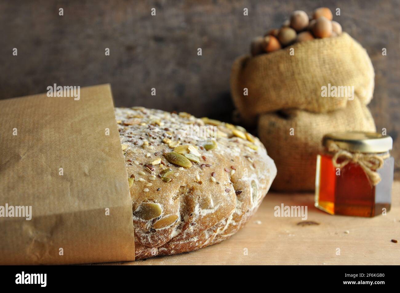Pane in carta con miele e noci, adagiato su una tavola di legno. Foto Stock