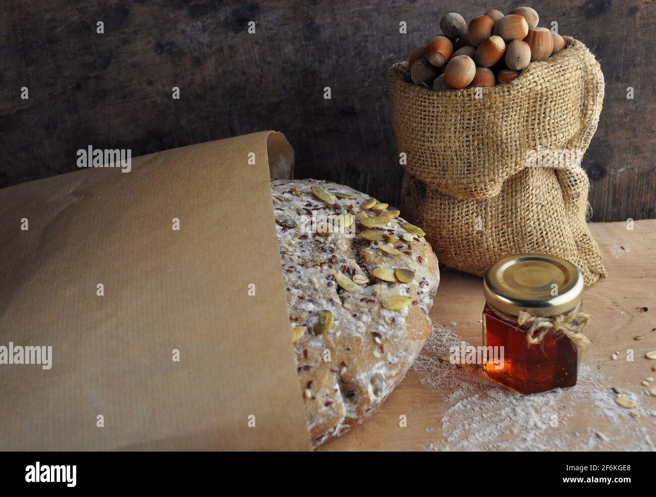Pane fatto in casa in carta su sfondo di legno. Noci e miele. Fonte di vitamine. Foto Stock