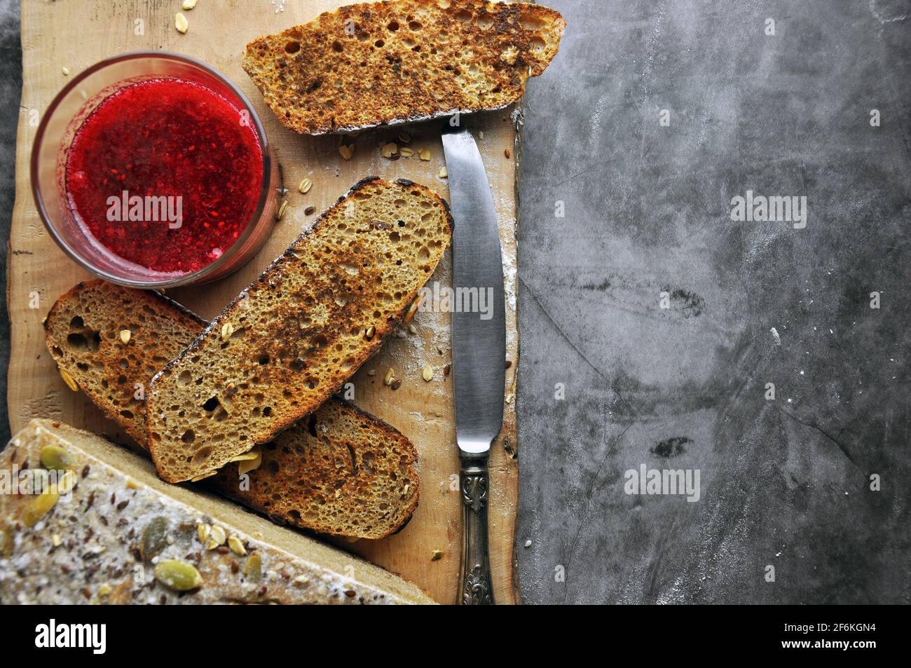 Pezzi di pane delizioso su una tavola di legno con marmellata di frutti di bosco. Vista dall'alto. Spazio vuoto per il testo. Foto Stock