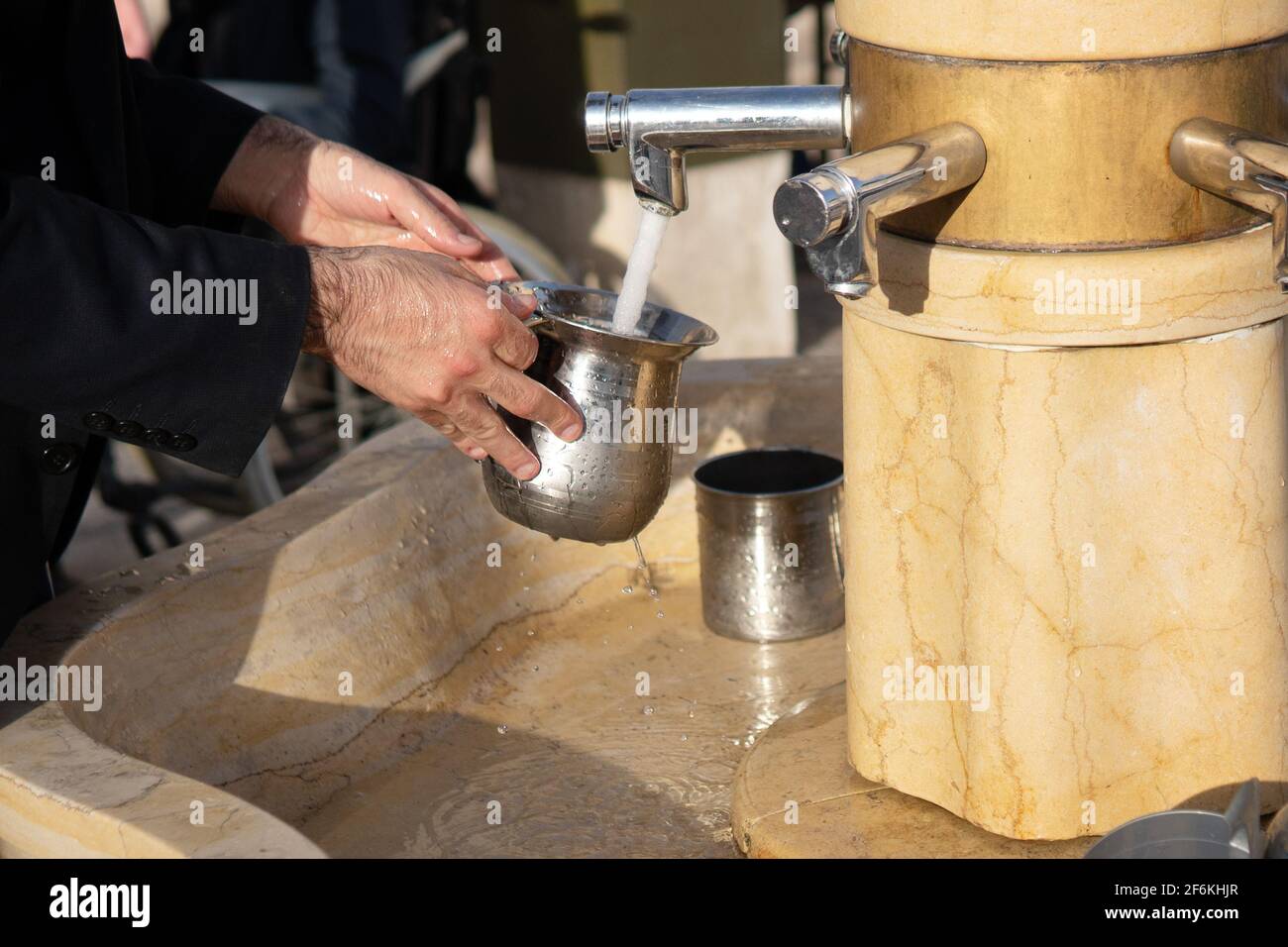 Mani di un uomo ebreo ortodosso che lavano le mani usando un coppa rituale tradizionale Foto Stock