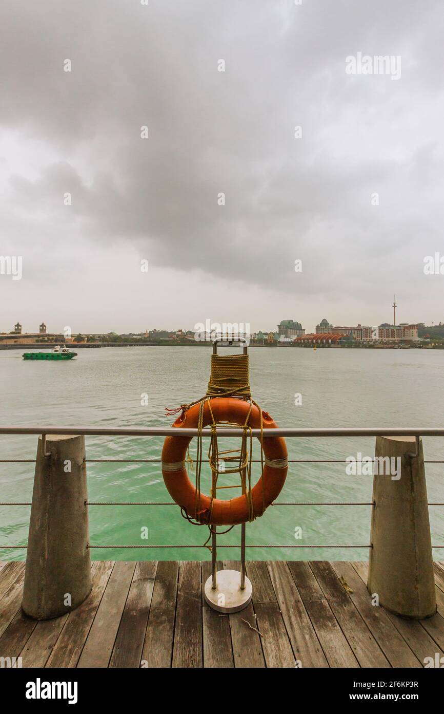 Un salvagente sul bordo di un molo vicino al porto di Singapore. Foto Stock