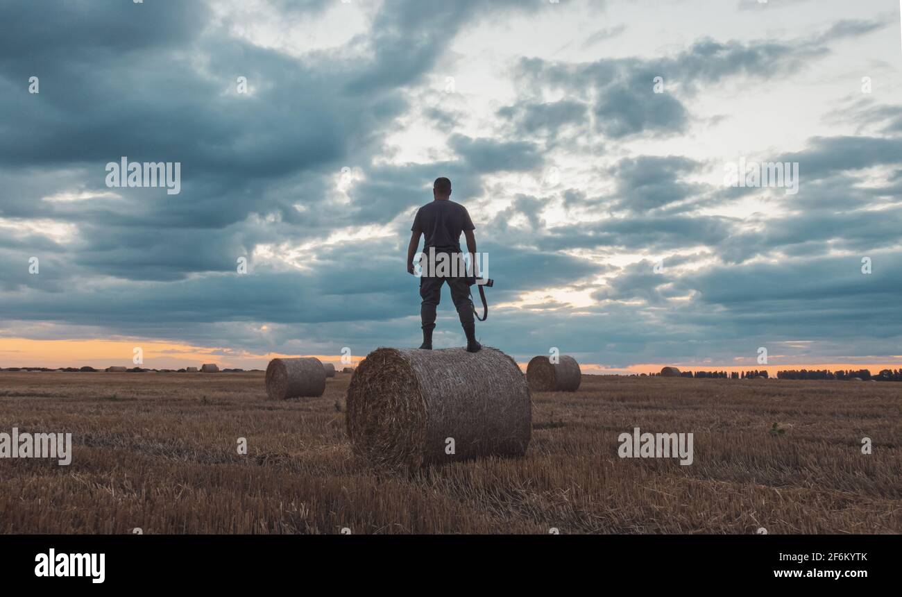 l'uomo con una macchina fotografica incontra il tramonto in piedi haystack Foto Stock