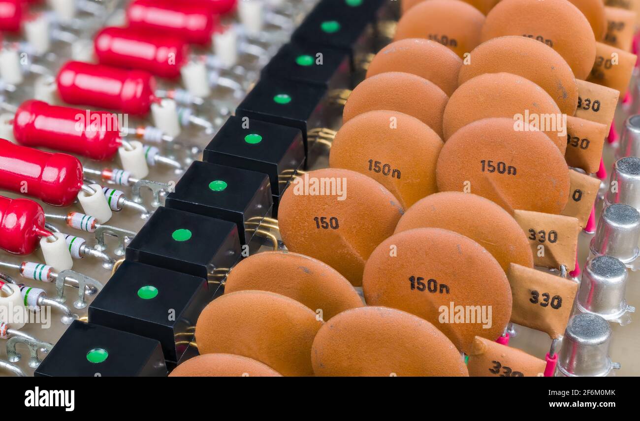 Dettaglio dei collegamenti dati isolamento galvanico su una scheda a circuito retro con vecchi componenti elettronici. Condensatore ceramico o accoppiatore ottico nero con luce LED. Foto Stock