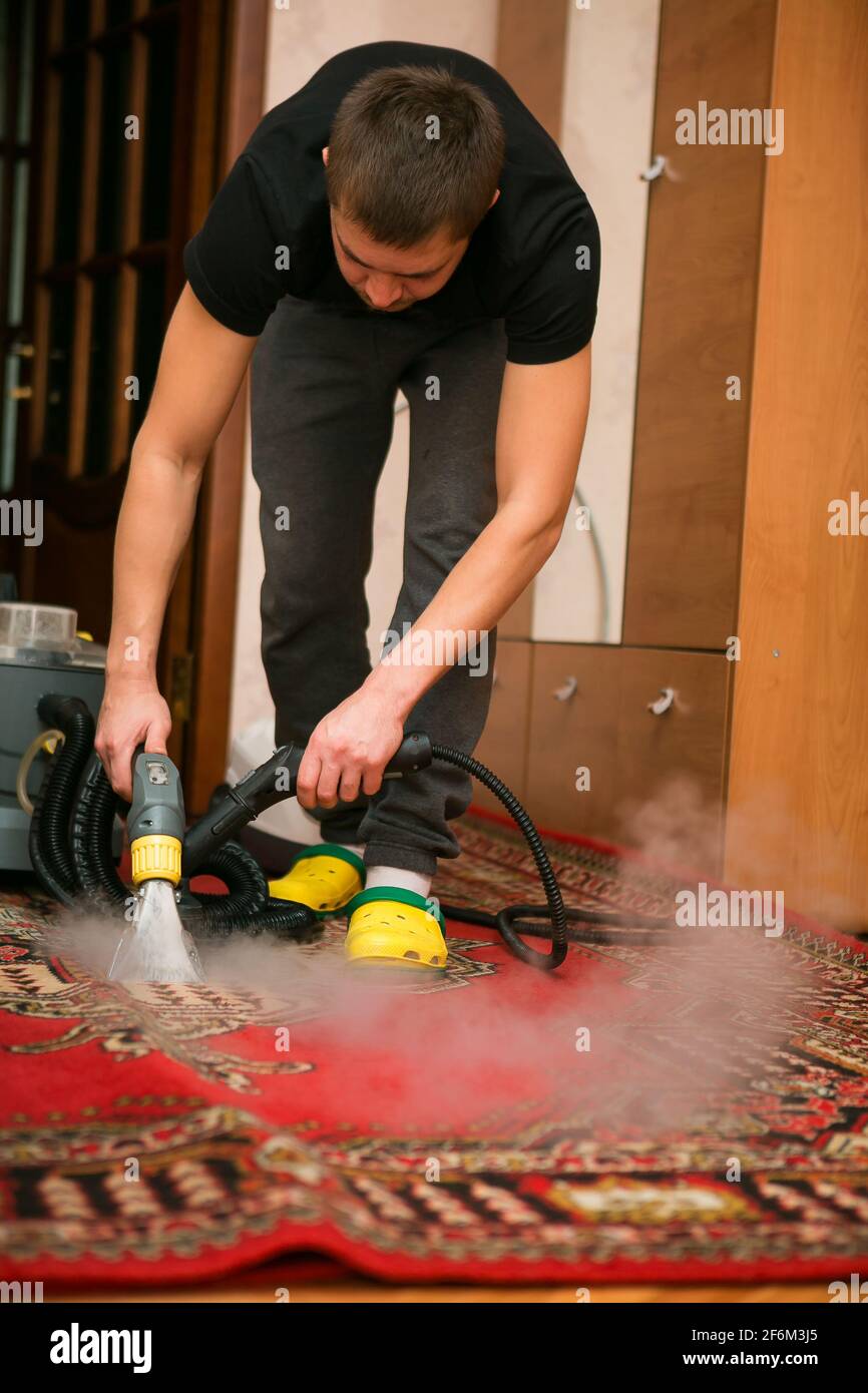 Il processo di pulizia dei tappeti con un aspirapolvere a vapore. Un  dipendente di un'azienda di pulizia pulisce il tappeto con il vapore Foto  stock - Alamy