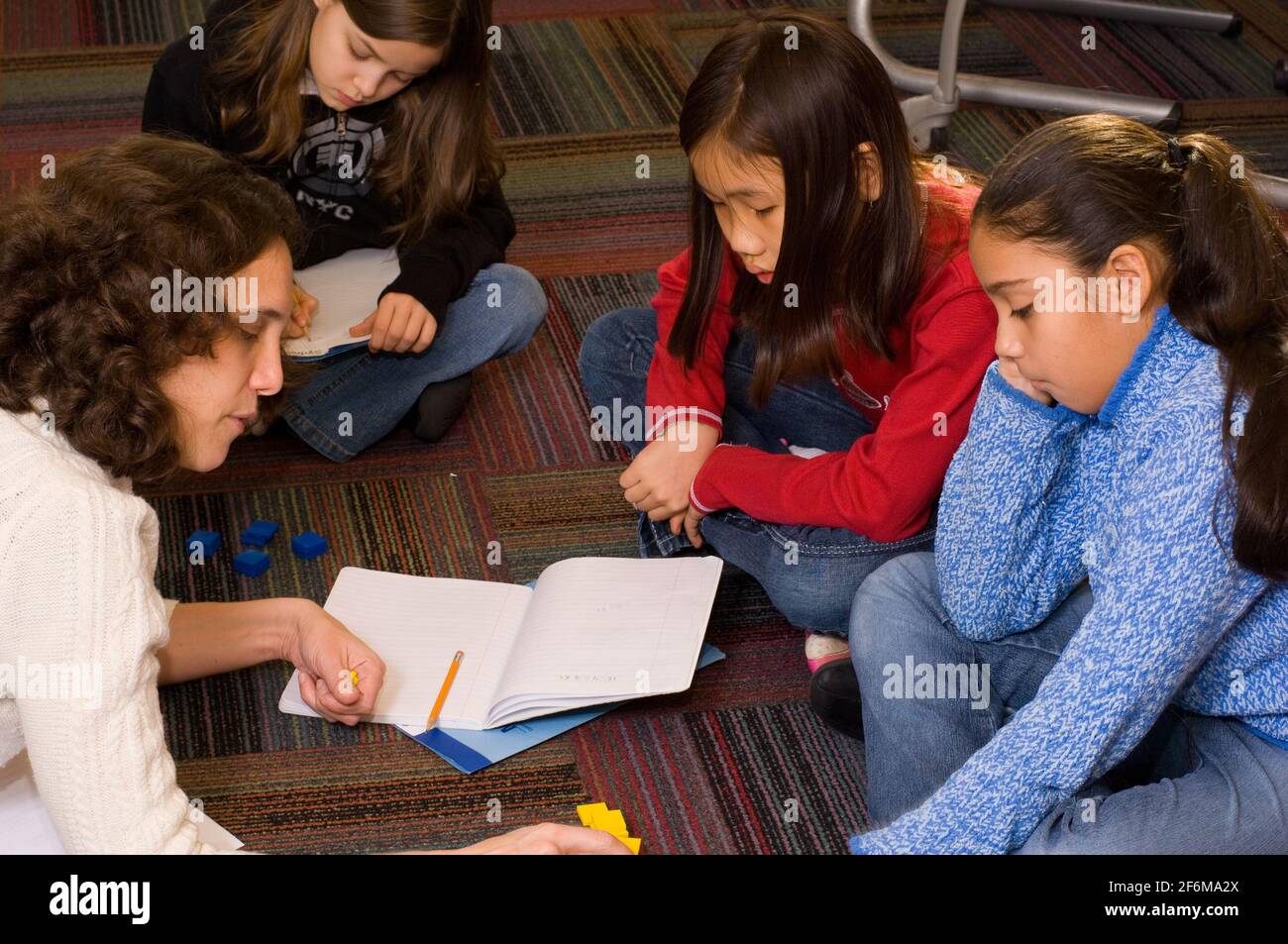 Scuola elementare indipendente grado 4 età 9-10 insegnanti di matematica femminile lavorare con due ragazze che usano manipolativi per lavorare sulla matematica concetti Foto Stock