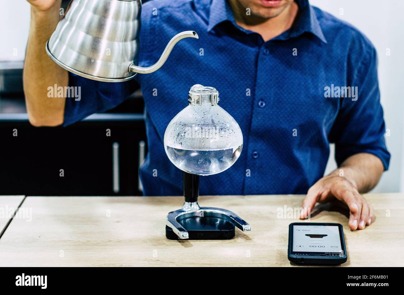 Macchina da caffè professionale - barista che utilizza un sifone per preparare caffè espresso caldo presso la caffetteria. Foto Stock