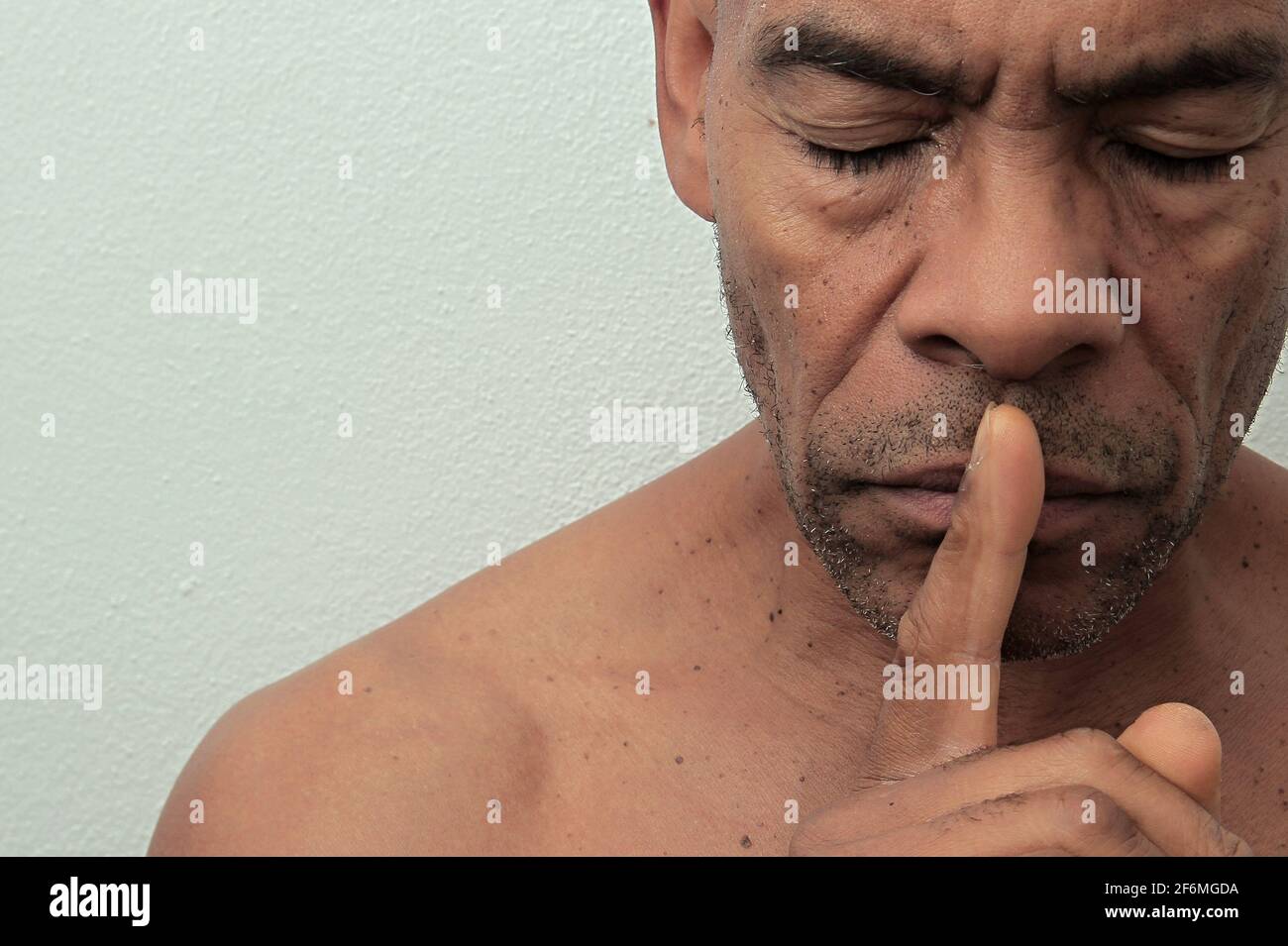 uomo con gesto dito sulla bocca che mantiene silenzioso su sfondo nero foto stock Foto Stock