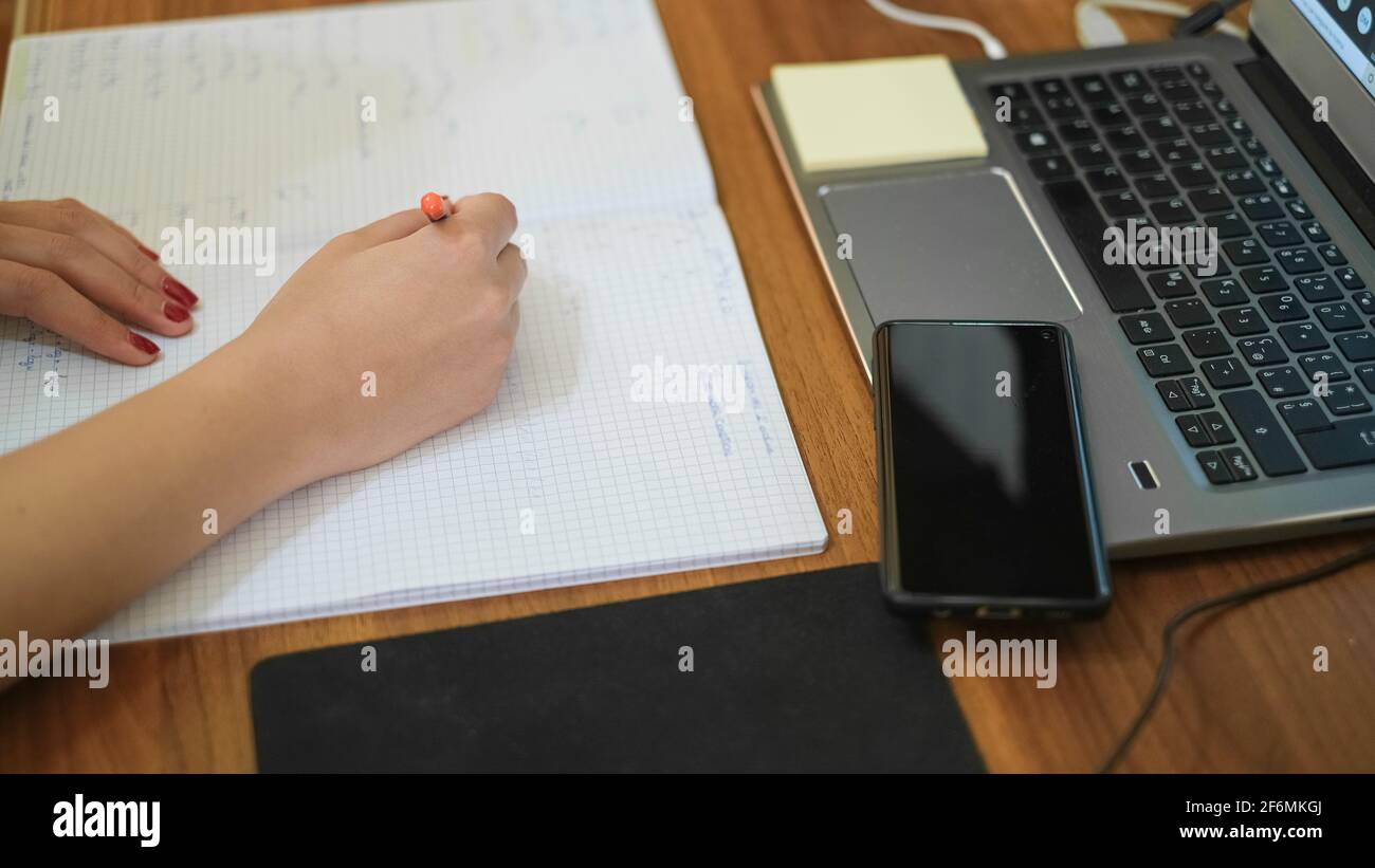 Donna che studia a casa mentre usa il notebook per la scuola remota, covid-19 pandemia di distanza sociale Foto Stock