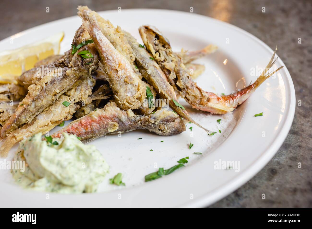 Pesce capelin fritto con erbe e salsa al limone e crema. Piatto di pesce. Piccolo pesce fritto, concetto di cibo sano. Foto Stock