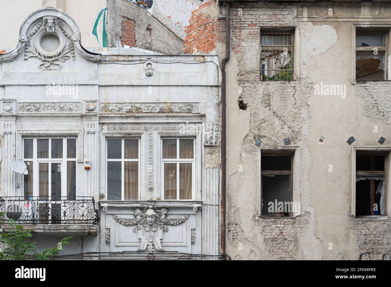 Due edifici a contrasto, nuovi (disevelati da finestre strappate) e vecchi (jugendstil o moderni, ben conservati), fianco a fianco, a Bucarest, Romania Foto Stock
