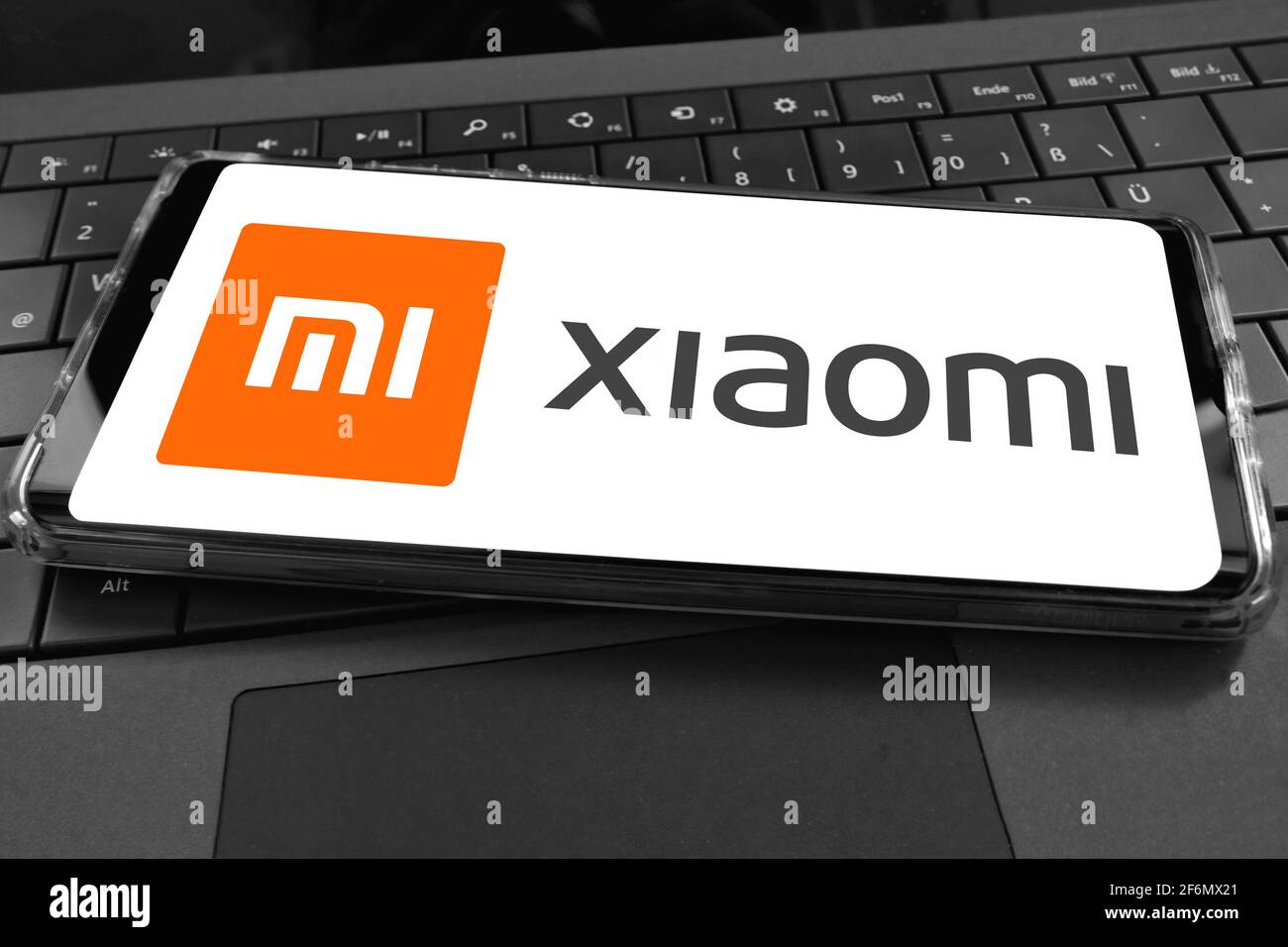 Primo piano dello schermo dello smartphone con il logo di xiaomi cinesi società di telefonia mobile con sfondo tastiera per computer Foto Stock