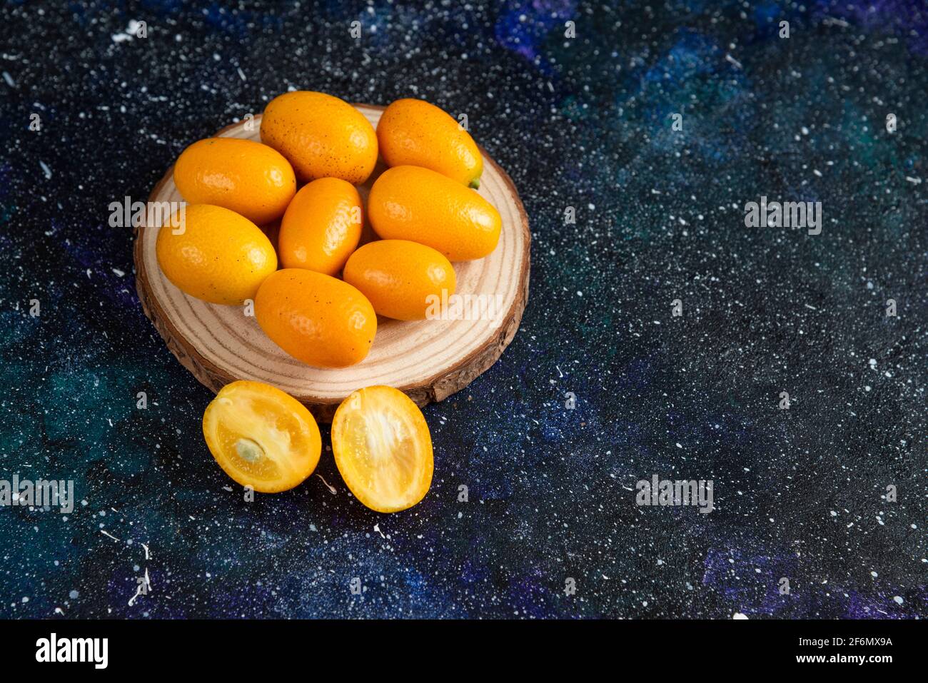 Primo piano foto di succosi kumquat su tavola di legno sopra sfondo blu Foto Stock