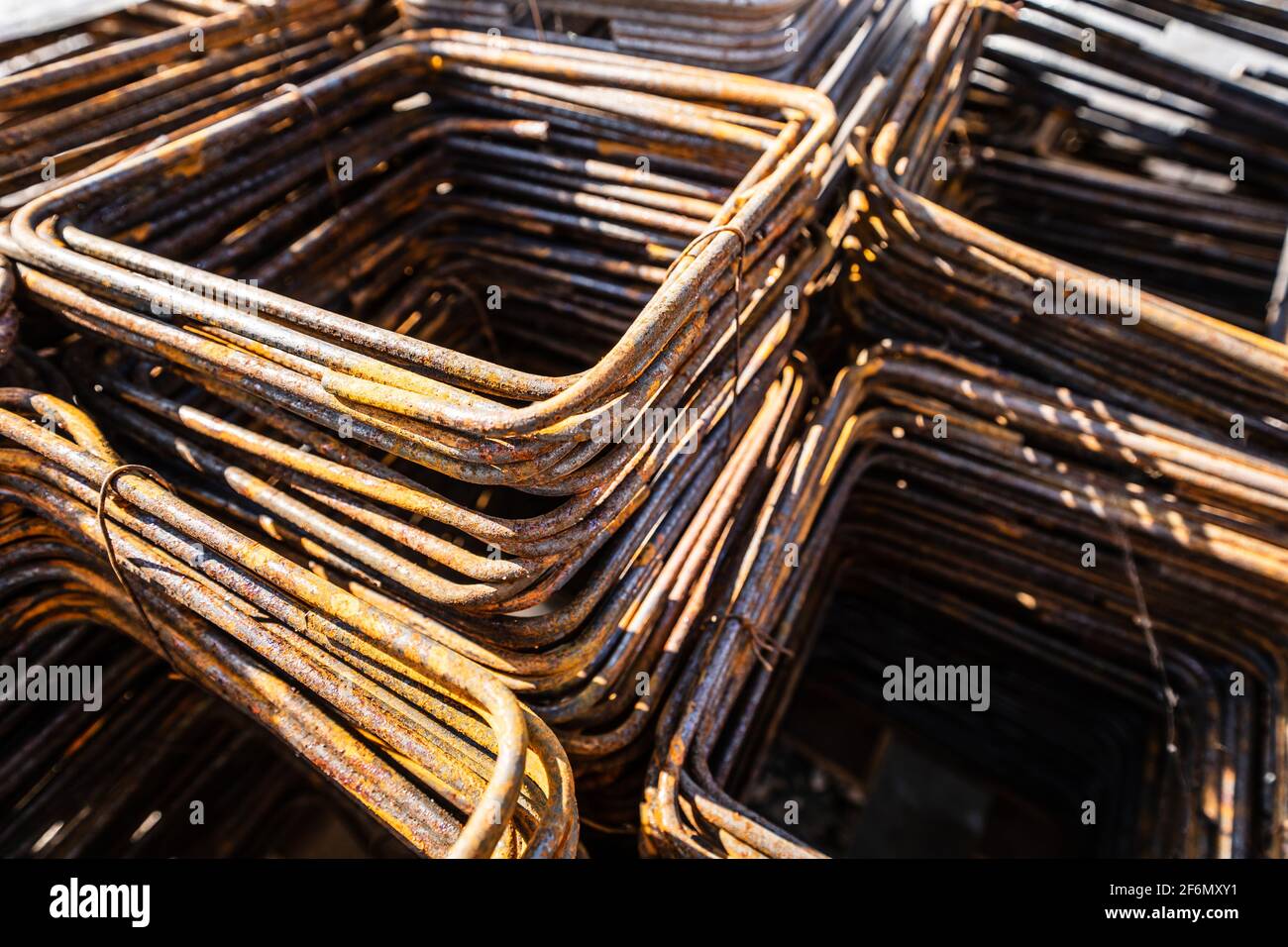 Primo piano sui telai in ferro dell'armatura da costruzione sul altri materiali da costruzione nel cantiere in giornata di sole Foto Stock