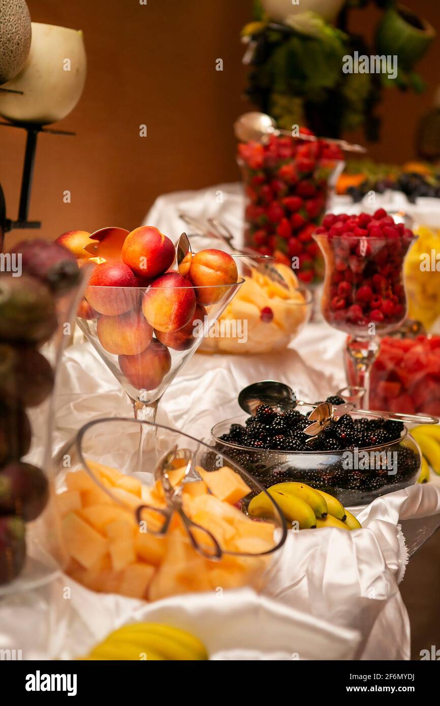 Cerimonia nuziale tavola di frutta con pesche, pere, fragole, more, melone e banane in contenitori di vetro Foto Stock
