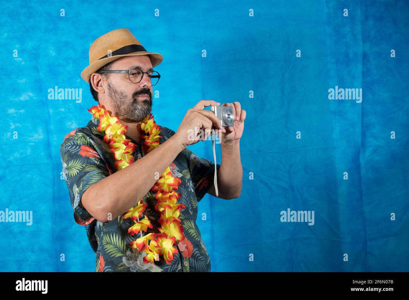 persona vestita come turista con camicia stampata e foto fotocamera in mano Foto Stock