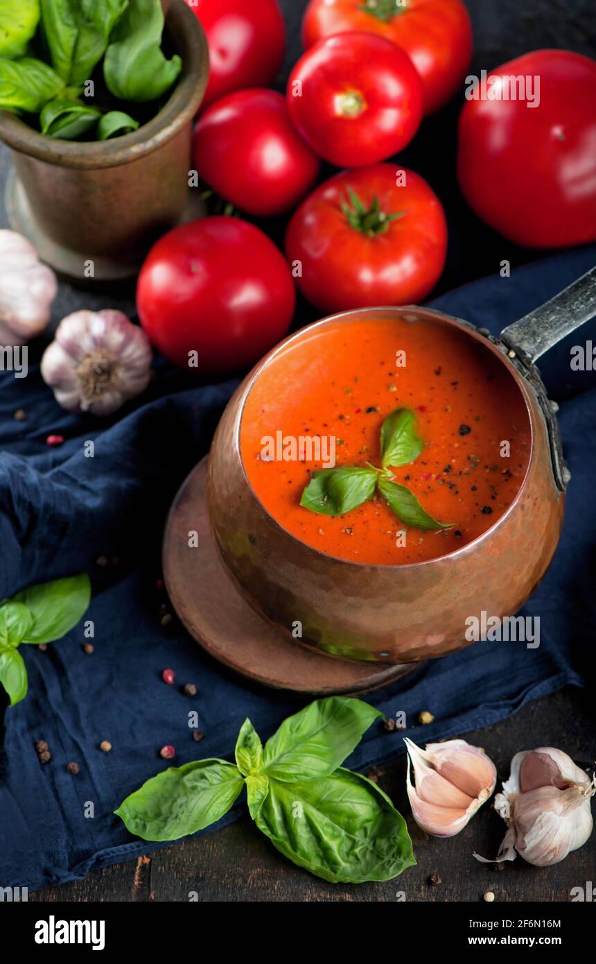 Zuppa tradizionale italiana di pomodoro gazpacho con basilico. Sfondo scuro Foto Stock