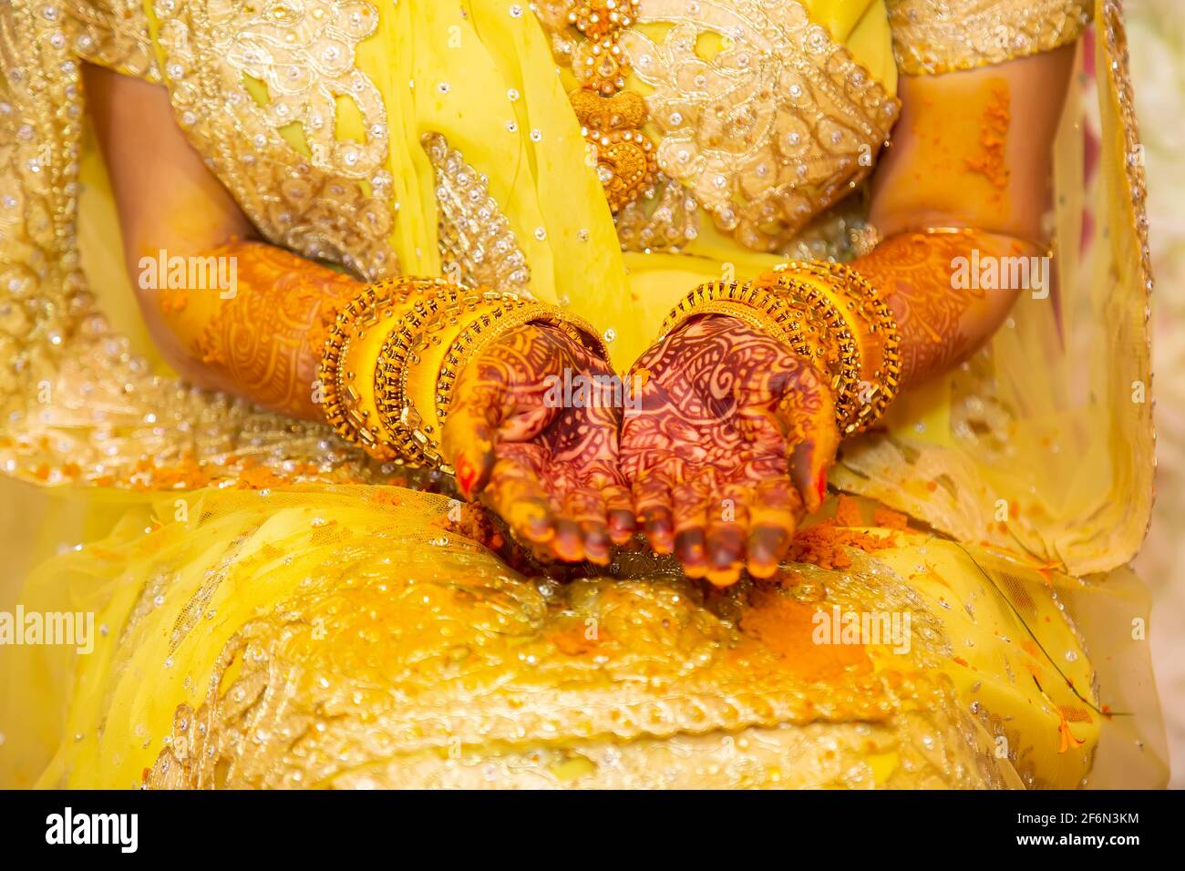 La mano della sposa indù dipinta con pasta curcuma fresca alla sua vigilia di nozze. Foto Stock