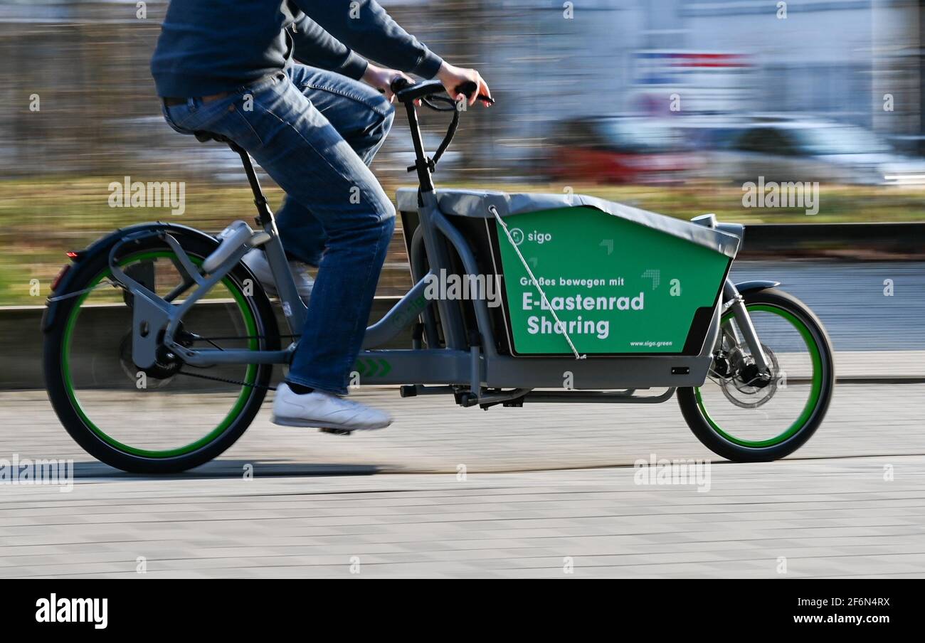 Darmstadt, Germania. 25 Marzo 2021. Tobias Lochen, fondatore della Sigo, che ha fondato Darmstadt, guida una e-bike (scatto a velocità più lunga dell'otturatore). SIGO gestisce sistemi di noleggio biciclette a trasporto chiuso in undici città. I fornitori commerciali e le nuove reti sono pronti a portare il cargo bike a un livello superiore, con stazioni fisse e noleggio all'ultimo minuto tramite app in qualsiasi momento della giornata, proprio come da tempo è stato standard per le biciclette a noleggio tradizionali. (A dpa 'Scene in sconvolgimento: Moto da trasporto sulla strada per il livello successivo') Credit: Arne Dedert/dpa/Alamy Live News Foto Stock