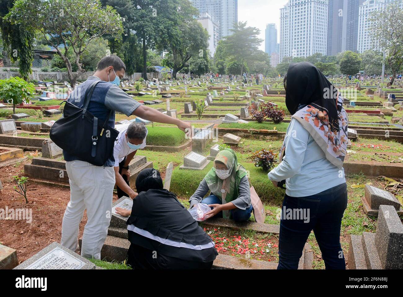 I residenti pregano nelle tombe dei loro parenti al Karet Bivak Public Cemetery (TPU), Giacarta, Indonesia, venerdì 2 aprile, 2021. Anche se il DKI Foto Stock