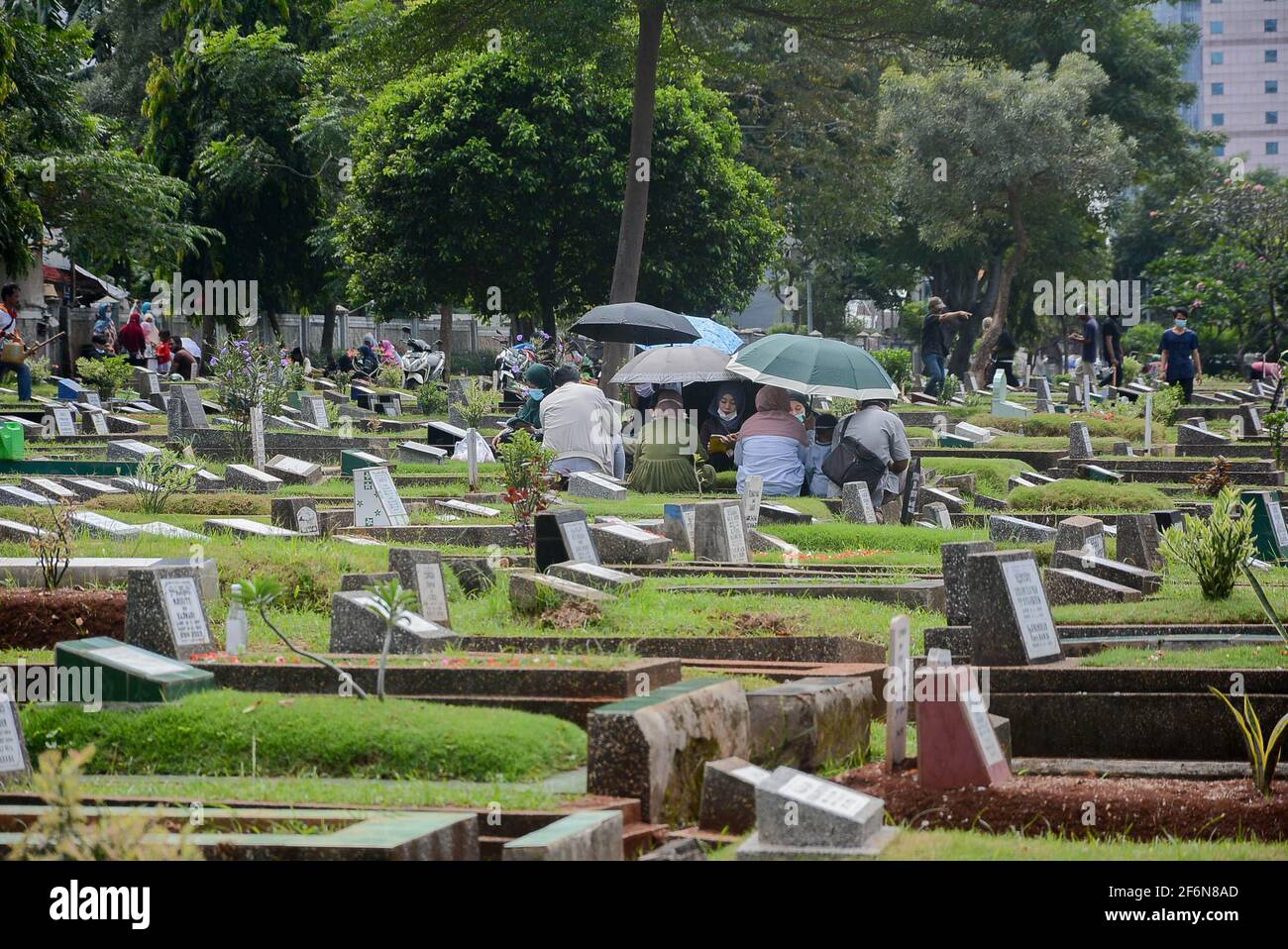 I residenti pregano nelle tombe dei loro parenti al Karet Bivak Public Cemetery (TPU), Giacarta, Indonesia, venerdì 2 aprile, 2021. Anche se il DKI Foto Stock