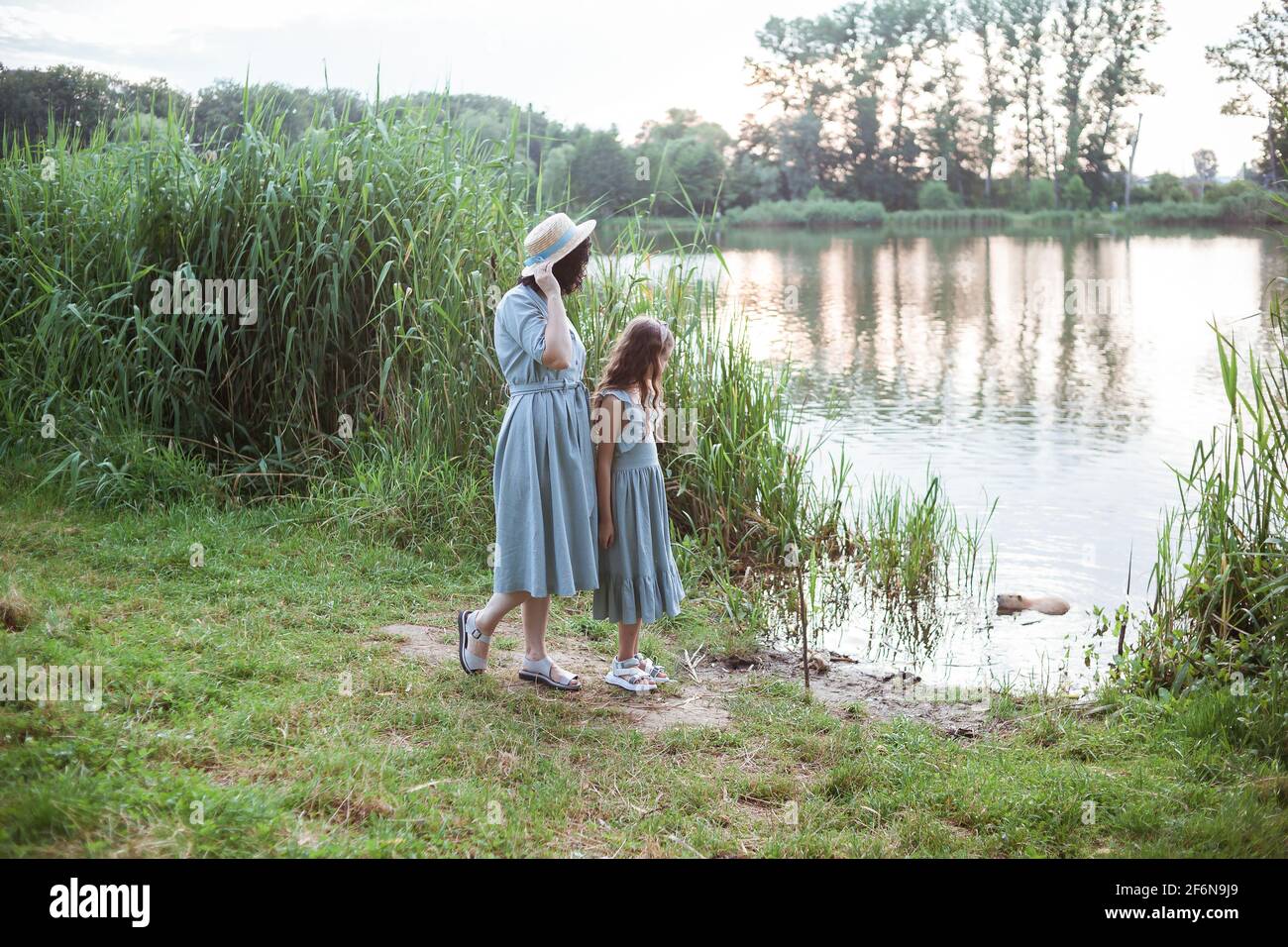 Una ragazza si trova sulla riva del lago e. guarda la nutria nell'acqua Foto Stock