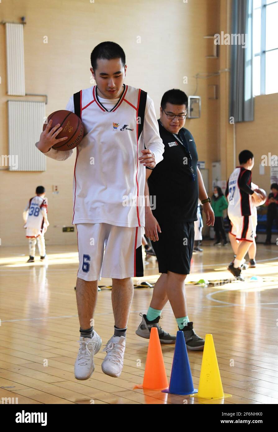 (210402) -- PECHINO, 2 aprile 2021 (Xinhua) -- Kang Rui (L, anteriore) partecipa a una sessione di allenamento di basket al Ditan Sports Center di Pechino, capitale della Cina, 24 marzo 2021. Kang Rui, 22 anni, è un poster designer di Foreign Language Teaching and Research Press (FLTRP) Bookstore a Pechino. Diagnosticato con autismo a cinque anni e mezzo, Kang Rui è stato inviato a studiare in un centro di istruzione speciale per i bambini autistici, dove ha fatto grandi progressi nelle abilità di apprendimento e di vita. Con la società della sua famiglia, Kang ha finito di scuola superiore professionale e ha mostrato talenti nel disegno e p Foto Stock