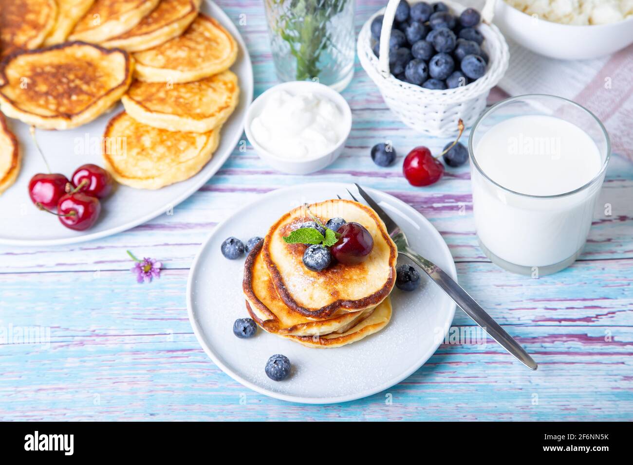 Frittelle di formaggio cottage (syrniki). Cheesecake fatti in casa da formaggio cottage con panna acida, bacche e latte. Piatto tradizionale russo. Primo piano. Foto Stock