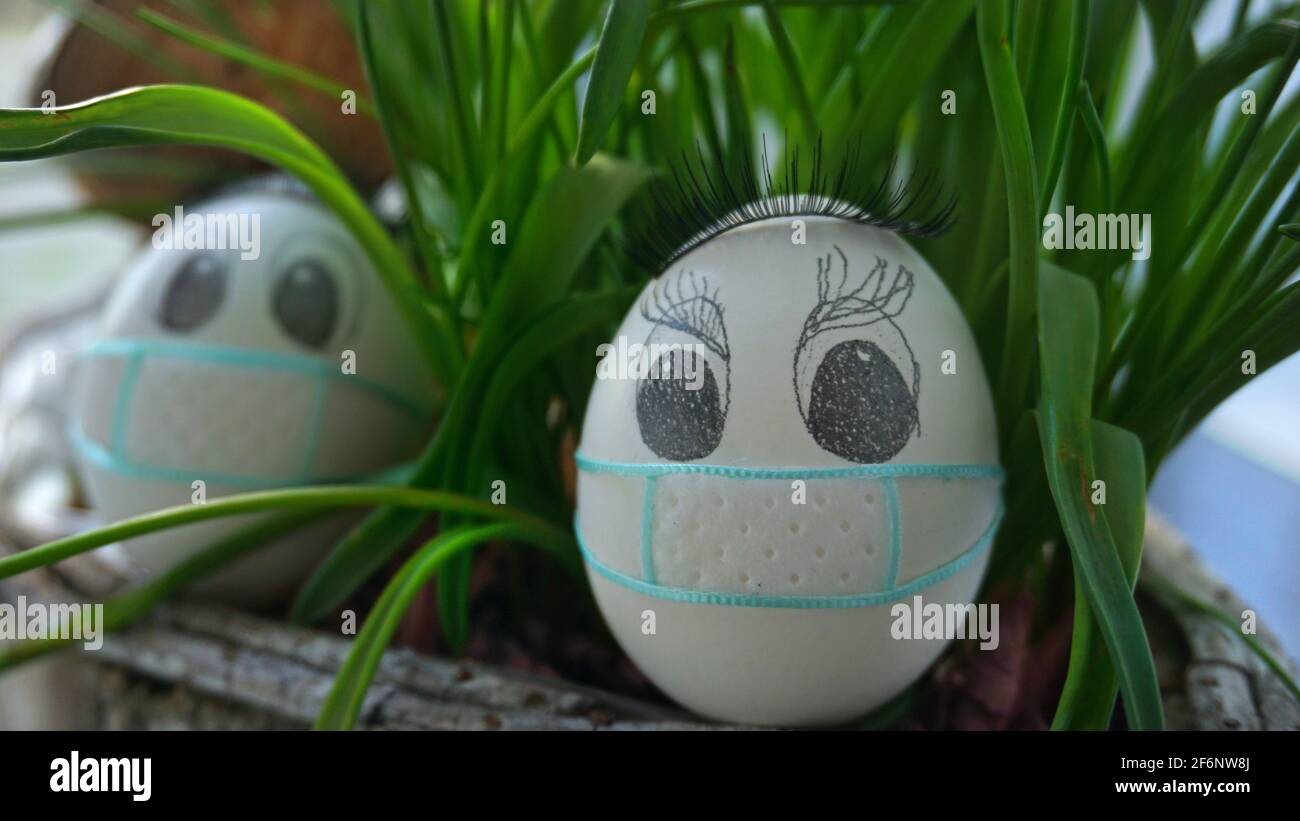 Uova di pollo di Pasqua con maschera protattiva in giardino, Pasqua 2021 Foto Stock