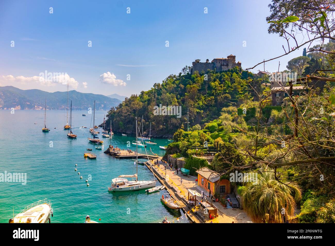 Bella vista colorata Golfo di Portofino Italia con il castello marrone sullo sfondo e le barche ancorate al piccolo porto pittoresco. Foto Stock