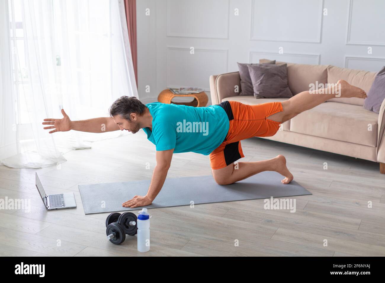 Allenamenti online a casa. Foto di un uomo di mezza età durante l'allenamento Balance davanti a un monitor laptop. Allenamenti ONLINE di yoga e pilates. Li sani Foto Stock