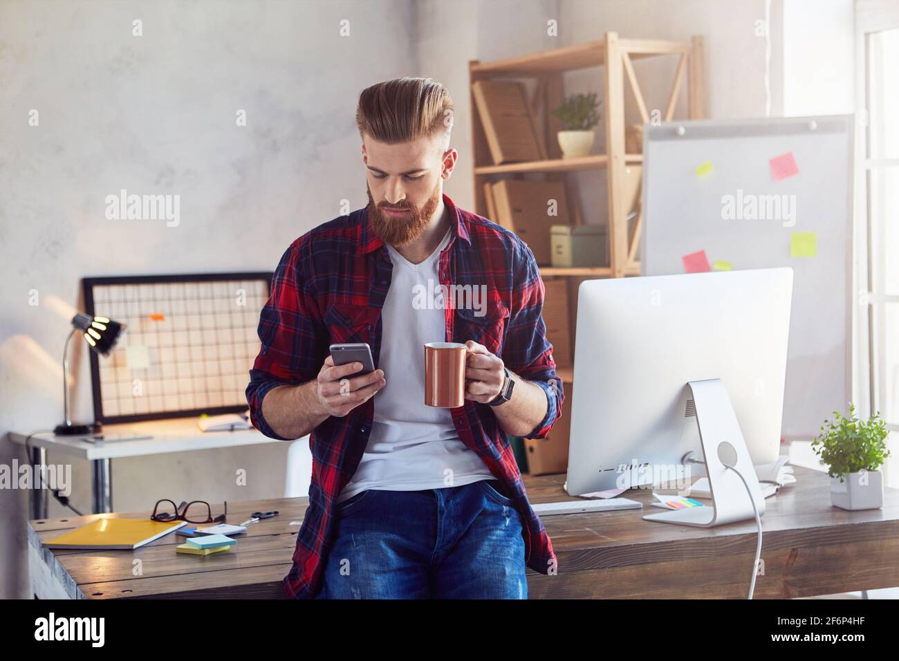 Elegante maschio che si rompe nel suo ufficio e che usa lo smartphone Foto Stock