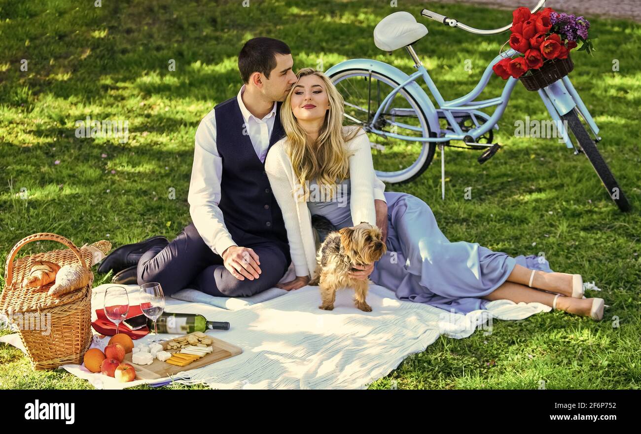 Questo è amore. Coppia felice in amore. Donna e uomo che si trovano nel parco e godersi la giornata insieme. san valentino picnic. Picnic romantico nel parco con il cane Foto Stock