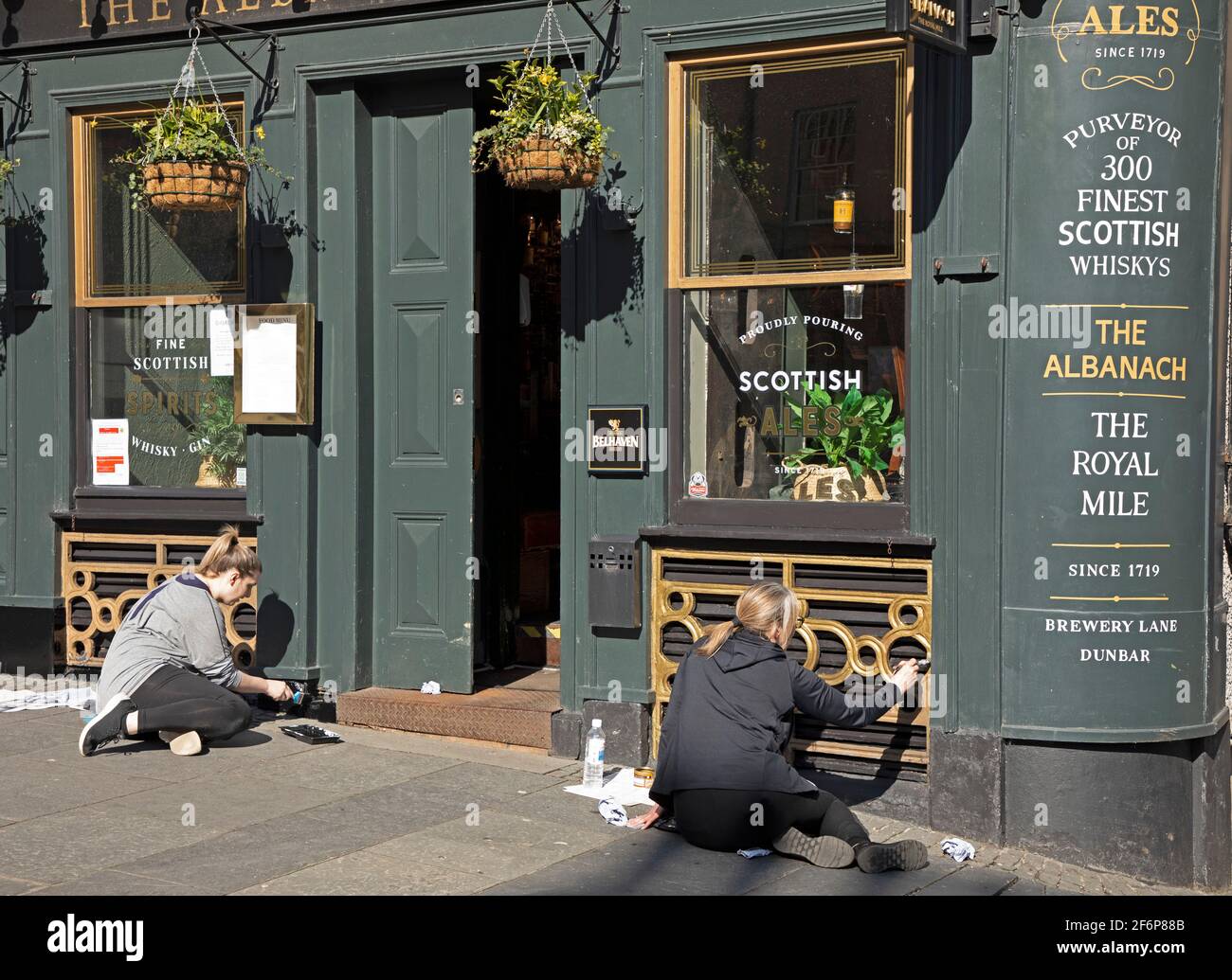 Centro di Edimburgo, Scozia, tempo del Regno Unito. 2 aprile 2021. Sole in tranquillo centro città per Pasqua Venerdì Bank Holiday, temperatura 9 gradi centigradi. Nella foto: Due membri del personale femminile del pub Albanach approfittano dell'opportunità di aumentare la vernice, in attesa che le restrizioni del Covid-19 vengano parzialmente revocate il 26 aprile. Foto Stock