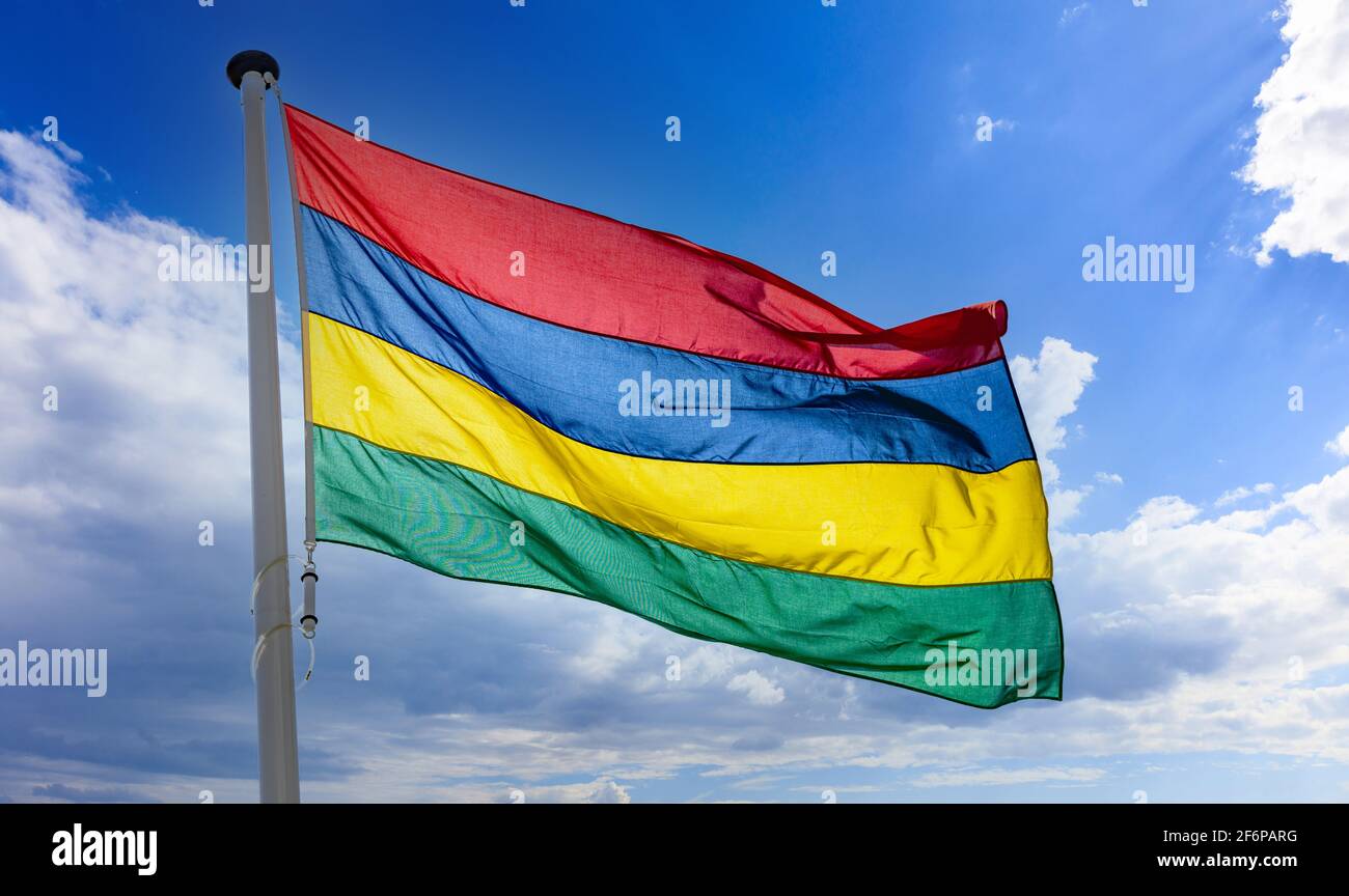 Bandiera di Mauritius, simbolo nazionale della Repubblica di Mauritius su un flagpole che oscilla contro il cielo blu nuvoloso Foto Stock