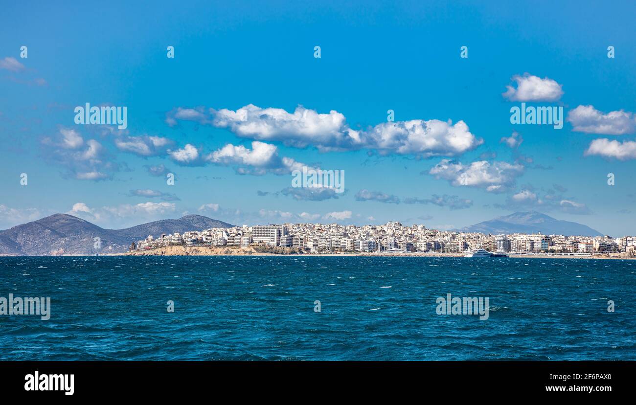Blu increspato mare, Pireo Grecia paesaggio urbano sfondo. Nuvole bianche su cielo limpido sulla superficie dell'acqua di mare. Foto Stock