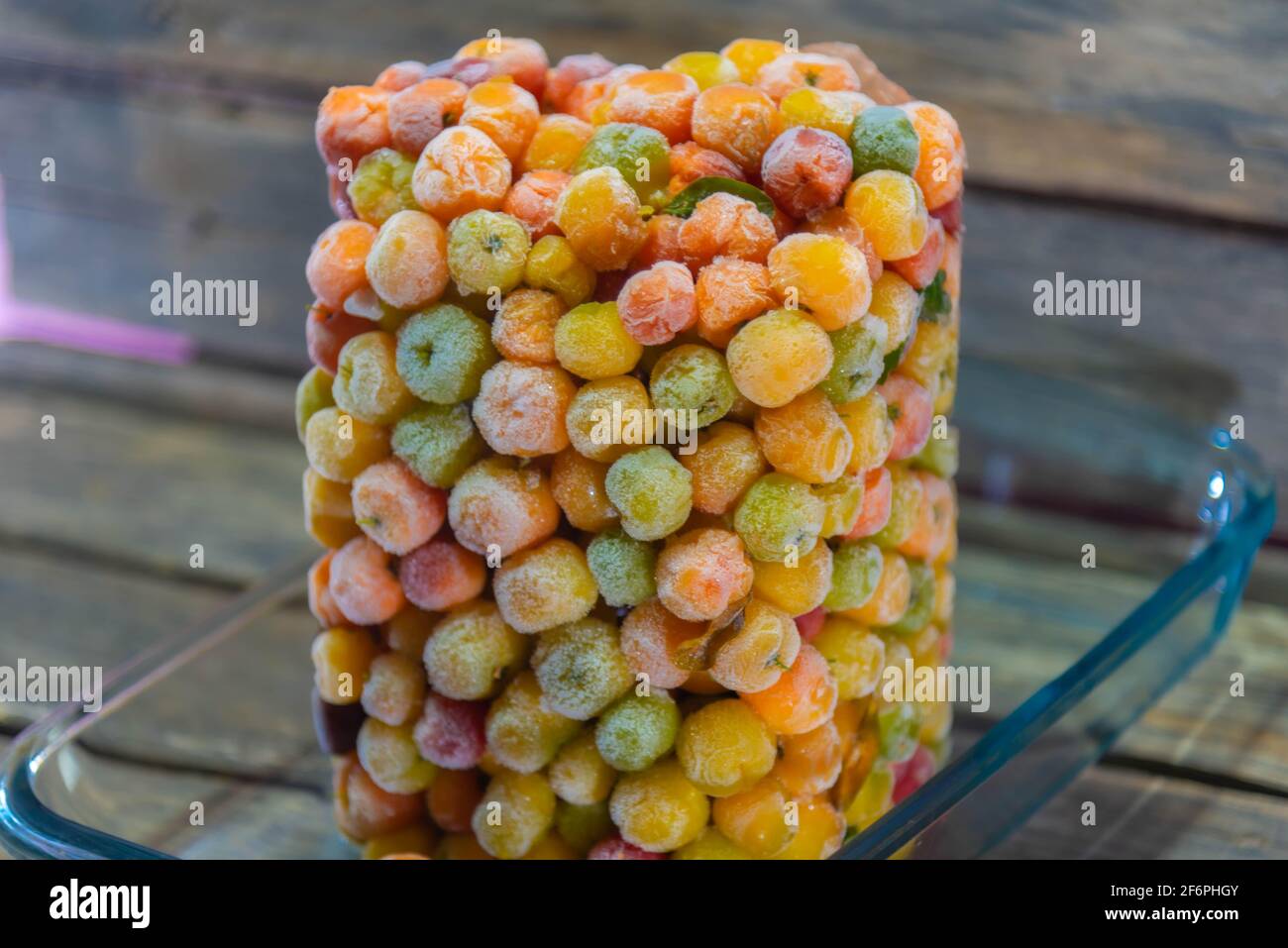 Frutta fresca di acerola surgelata su sfondo ligneo. Fonte di succo di antiossidanti, in quanto è il secondo frutto con il più alto contenuto di vitamina C. Foto Stock