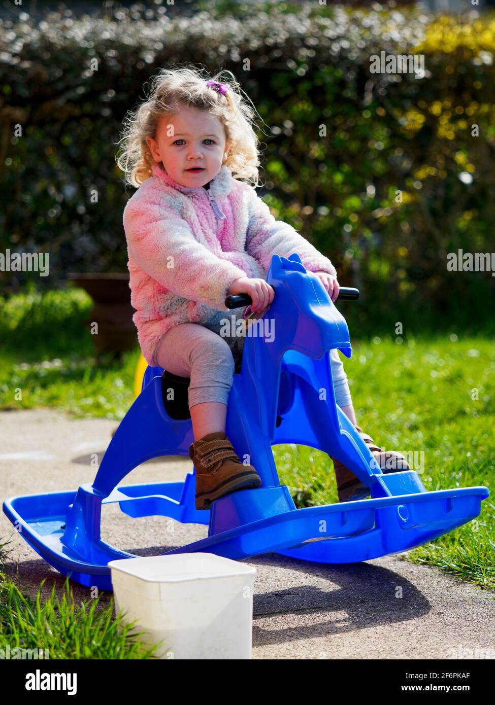 Toddler su un cavallo dondolante nel giardino, Regno Unito Foto Stock