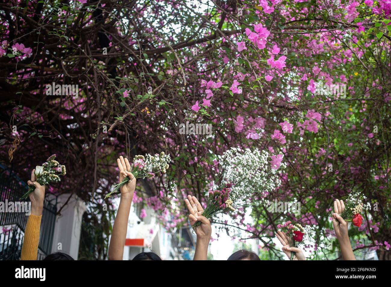 La gente saluta a tre dita mentre tiene i fiori in memoria delle vittime delle violente proteste contro l'acquisizione militare del 1° febbraio. Venerdì, la popolazione del Myanmar ha dato i fiori in luoghi pubblici in memoria delle vittime delle violente proteste contro l'acquisizione militare del 1° febbraio. Gli organizzatori hanno chiesto un 'sciopero dei fiori' dicendo che questi dovrebbero essere posati in luoghi come i parchi e le fermate dell'autobus in ricordo di 'eroi che non possono tornare a casa'. Foto Stock