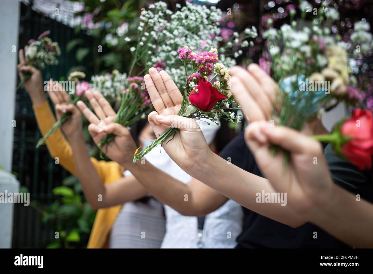 La gente saluta a tre dita mentre tiene i fiori in memoria delle vittime delle violente proteste contro l'acquisizione militare del 1° febbraio. Venerdì, la popolazione del Myanmar ha dato i fiori in luoghi pubblici in memoria delle vittime delle violente proteste contro l'acquisizione militare del 1° febbraio. Gli organizzatori hanno chiesto un 'sciopero dei fiori' dicendo che questi dovrebbero essere posati in luoghi come i parchi e le fermate dell'autobus in ricordo di 'eroi che non possono tornare a casa'. (Foto di Theint Mon Soe/SOPA Images/Sipa USA) Foto Stock