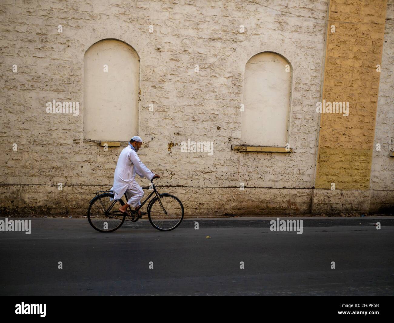 Mumbai, India - 7 gennaio 2021 : uomo musulmano di vecchia età che indossa abiti islamici tradizionali e cappello del cranio che cavalcano una bicicletta per le strade di Mumbai Foto Stock