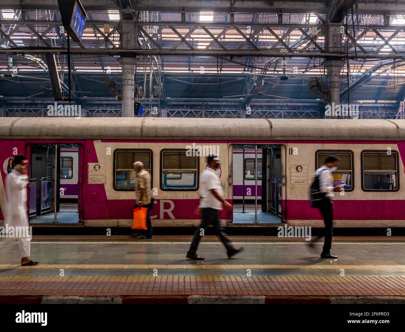 Mumbai, India - 7 gennaio 2021 : passeggeri non identificati (volti sfocati) che camminano su un binario alla stazione CST, una delle stazioni ferroviarie più trafficate per Foto Stock