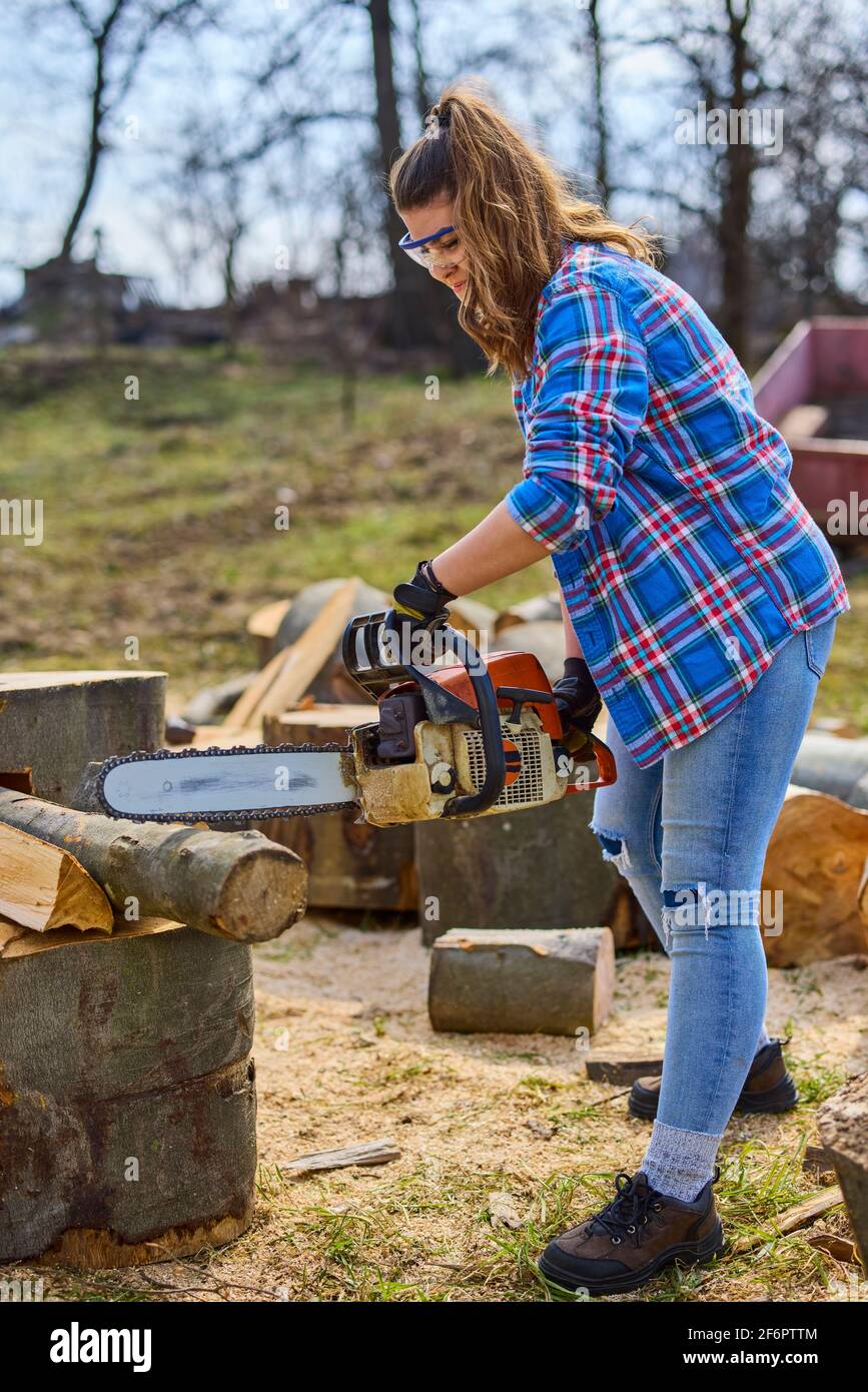 Giovane Donna con motosega per tagliare un log per legna da ardere Foto  stock - Alamy