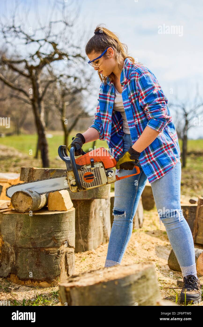 Giovane Donna con motosega per tagliare un log per legna da ardere Foto  stock - Alamy