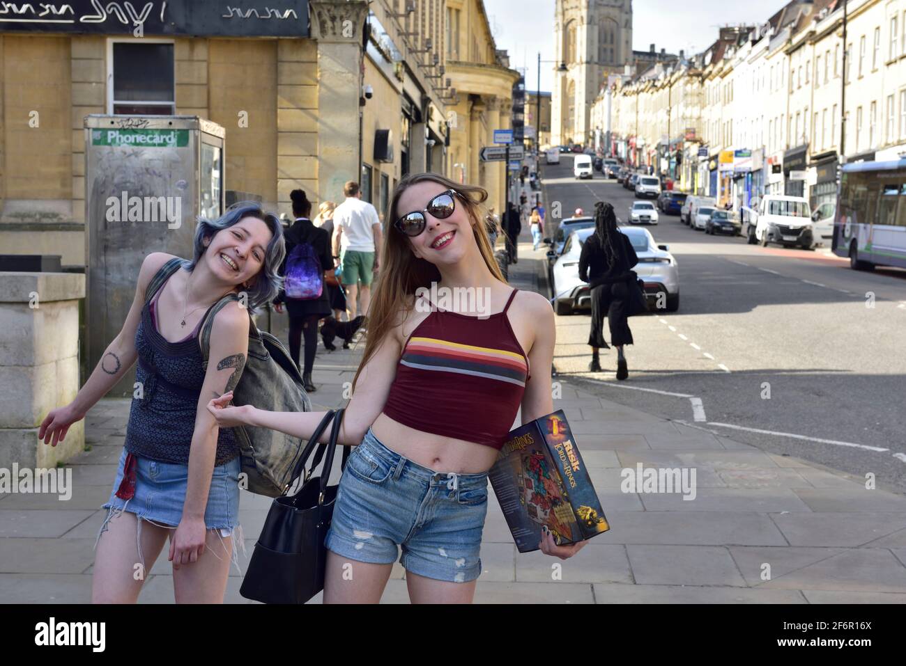 Due giovani donne che si godono il sole e la libertà Bristol Park Street dopo il Regno Unito covid lock giù alleviato Foto Stock