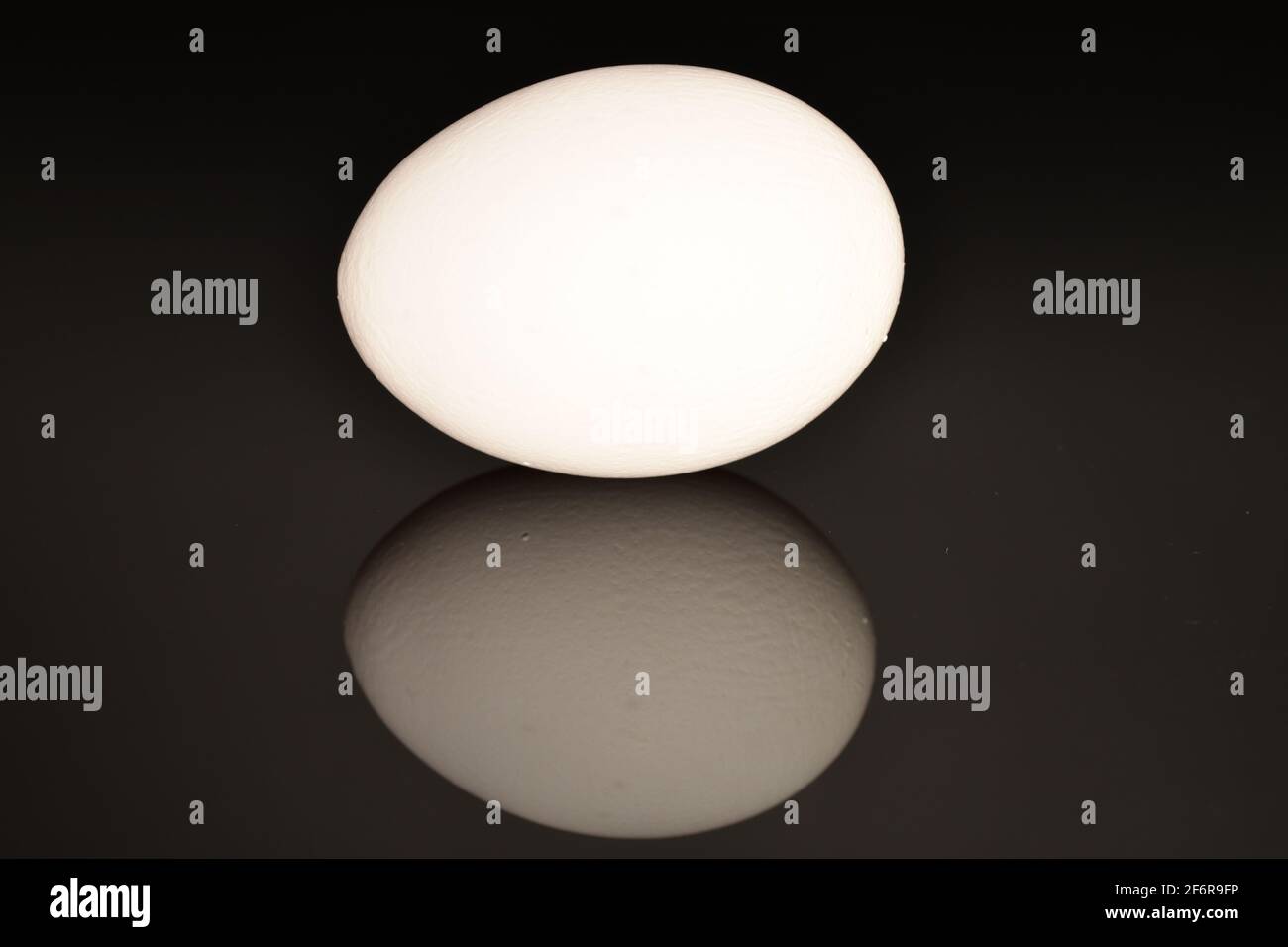 Un uovo di pollo bianco, fresco, ovale, biologico, su sfondo nero. Foto Stock
