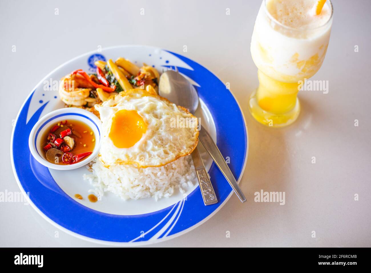 Un piatto di riso bollito, uova fritte e gamberi con salsa su un piatto,  accanto ad un frullato di ananas, cibo tailandese in un caffè Foto stock -  Alamy